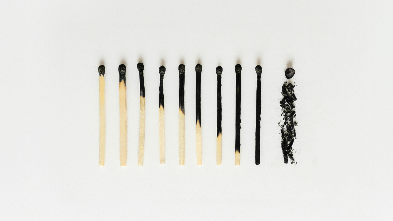 a group of matches on a white surface ranging from just a burnt tip to a line of black ash
